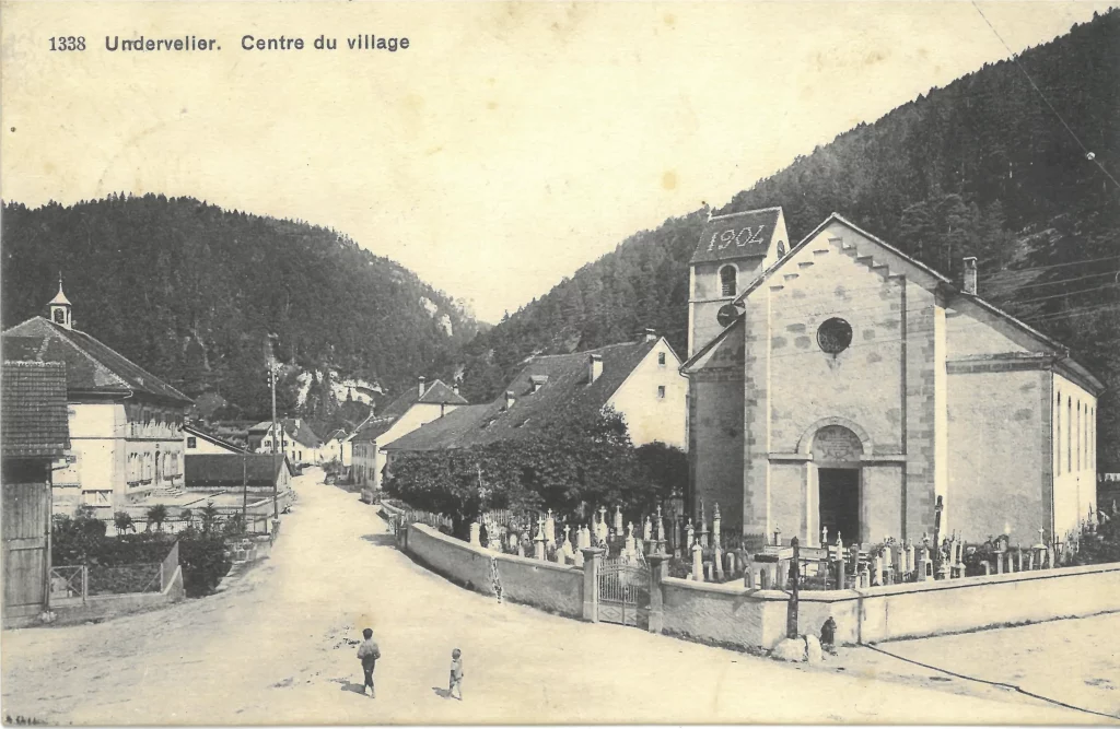 Deux passants, dont au moins un enfant, traversent le coeur du village, sur ce cliché.